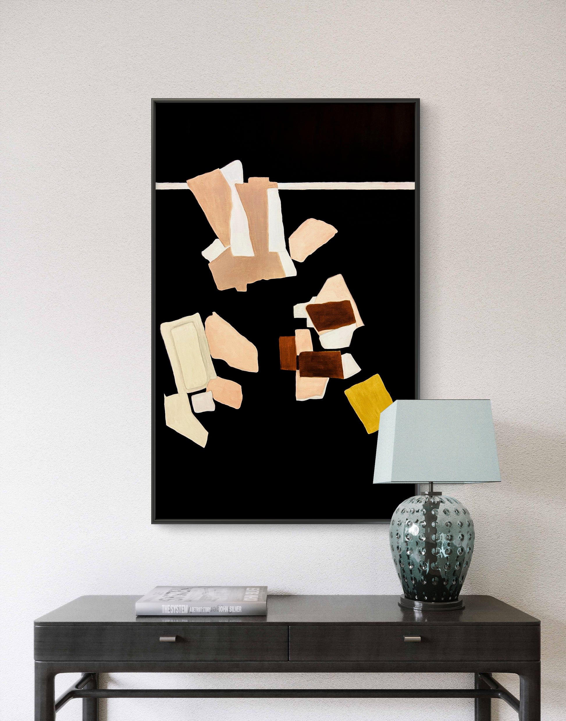 Abstract art piece on a wall above a console table with a lamp.